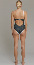 Person wearing a black and white patterned swimsuit on a plain background